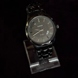 A sleek black Rado wristwatch with a metal strap displayed on a transparent stand against a dark background.